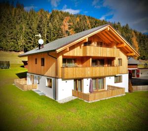 a house with a wooden roof and a green lawn at Appartement Förra in Valle Di Casies