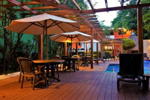 eine Außenterrasse mit Tischen, Stühlen und Sonnenschirmen in der Unterkunft Hotel Maya Tulipanes Palenque in Palenque