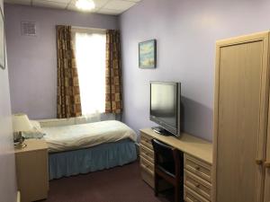 Dormitorio pequeño con cama y TV en St. James's Guest House, en Londres