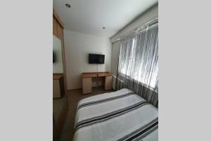 a bedroom with a bed and a window with a television at Луксозен апартамент с WiFi на 10км от Боровец in Samokov