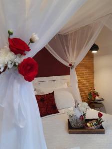 パラチにあるMagias de Paraty Ecopousadaのベッドルーム1室(赤と白の花のベッド1台付)