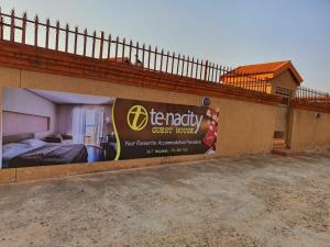 a guest house with a sign on the side of it at Tenacity Guesthouse - Riviera Park in Mahikeng