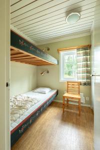 a bedroom with a bunk bed and a chair at Ekesberget Stugby stuga 3 in Ekshärad