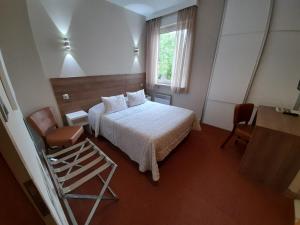 ein Schlafzimmer mit einem Bett, einem Fenster und einem Stuhl in der Unterkunft Hôtel Restaurant À L'Etoile in Merkwiller-Pechelbronn