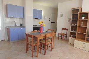 a kitchen with a table and chairs and blue cabinets at Nettuno 9C in Lido di Pomposa