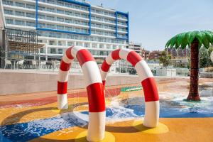a pool with a water park with red and white umbrellas at L'Azure Hotel 4* Sup in Lloret de Mar