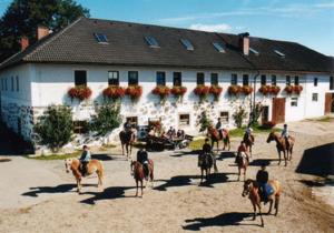 un grupo de personas montando caballos delante de un edificio en Reiterhof Stöglehner, en Rainbach im Mühlkreis