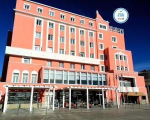 um grande edifício laranja com muitas janelas em THE ONE Grand Hotel da Póvoa na Póvoa do Varzim