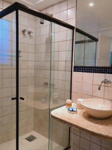 uma casa de banho com uma cabina de duche em vidro e um lavatório. em Porto Mar de Búzios em Búzios