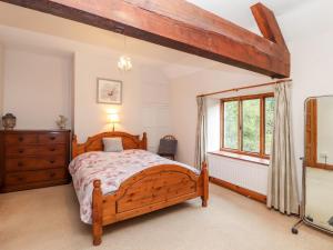 une chambre avec un lit en bois et une fenêtre dans l'établissement Abbey Cottage, à Denbigh