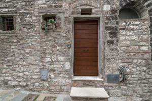 グッビオにあるMamihouseの木製のドアと窓が2つある石造りの建物