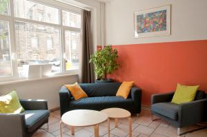 uma sala de estar com um sofá e duas cadeiras em Happy Hotel Berlin em Berlim