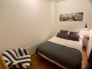 1 dormitorio con 1 cama y 1 silla en Apartamentos Los Lagos, en Benasque