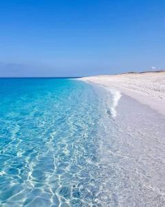 einen Strand mit klarem blauen Wasser und weißem Sand in der Unterkunft Villa Cesarea in Porto Cesareo