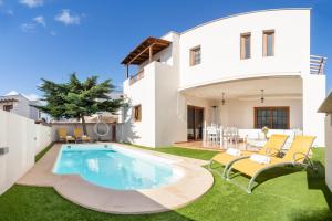 a villa with a swimming pool in front of a house at Valentina Villa Private Pool Garden in Costa Teguise