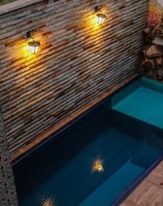 a swimming pool with lights on a brick wall at Pousada Araras in Alto Paraíso de Goiás