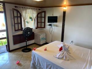 ein Schlafzimmer mit einem weißen Bett mit einem Kleid darauf in der Unterkunft Guesthouse Saint Tropez in Arraial do Cabo