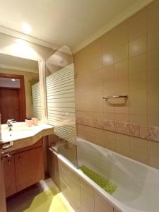a bathroom with a tub and a sink and a mirror at Garden's Apartment in Funchal
