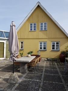 a yellow house with a table and an umbrella at Beachhouse Langeland in Tranekær