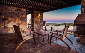 a patio with chairs and a table and a fireplace at Keros Blue - Luxury in Wilderness in Kalliópi