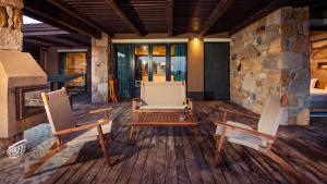two chairs and a table on a porch with a stone wall at Keros Blue - Luxury in Wilderness in Kalliópi