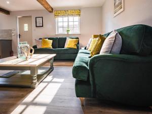 a living room with a green couch and a table at Farmcourt Barn 57 Eastfield Lane in Lincoln