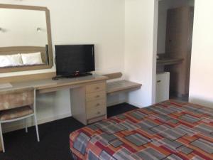 Nunawading Motor Inn في Nunawading: غرفة في الفندق مع مكتب مع سرير ومرآة