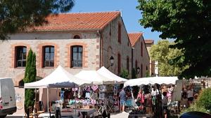 een markt met witte tenten voor een gebouw bij Les Chênes-Lièges in Laroque-des-Albères