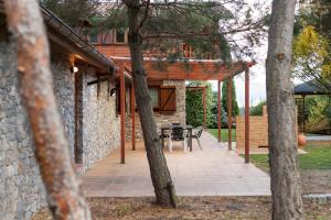 ein Steinhaus mit einer Terrasse mit einem Tisch in der Unterkunft El Refugi de les Basses Apartament in Campelles
