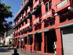 een rood gebouw waar mensen voor lopen bij Hotel Royal Palace in Guatemala