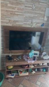 um centro de entretenimento com uma televisão de ecrã plano na parede em Sonho Azul em Ubatuba