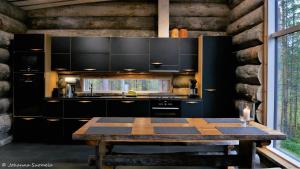 a kitchen with black cabinets and a wooden table at Villa Konttaisenranta in Ruka