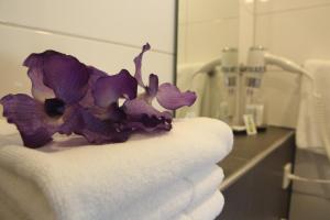 een stapel handdoeken en paarse bloemen in de badkamer bij Herberg Erve Kots Logement in Lievelde