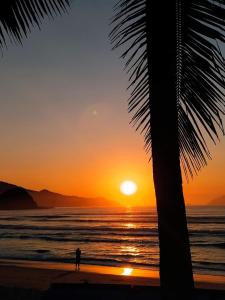 una persona de pie en la playa mirando la puesta de sol en Sonho Azul, en Ubatuba