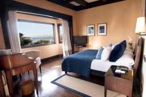 a bedroom with a bed and a desk and a window at Hotel Casa Higueras in Valparaíso