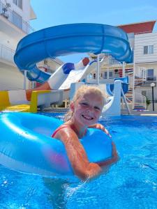 a young girl riding on a blue raft in a swimming pool at Antalya belek 1 Nirvana club first floor two bedrooms pool view with water slide close to center in Belek