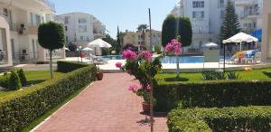 a brick walkway next to a courtyard with pink flowers at Antalya belek 1 Nirvana club first floor two bedrooms pool view with water slide close to center in Belek
