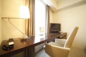 um quarto de hotel com uma secretária com um candeeiro e uma cadeira em Richmond Hotel Premier Sendai Ekimae em Sendai