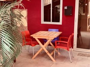 een houten tafel en stoelen voor een rode muur bij Chez Titi in Saint-Louis