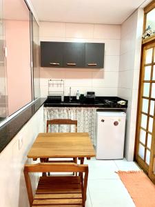 eine Küche mit einem Holztisch und einem weißen Kühlschrank in der Unterkunft Sunset Maresias- Casas e Chalés C1 in Maresias