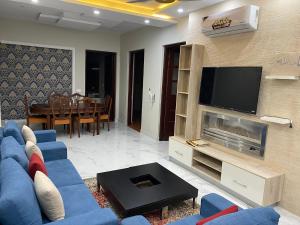 a living room with a blue couch and a tv at Bahria V&A Phase-2 in Rawalpindi