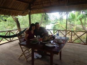 a man and woman sitting at a table with food at Phuong Thao Homestay in Vĩnh Long