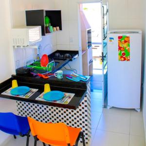 a kitchen with a counter with chairs and a refrigerator at Kitnet Maitinga in Bertioga