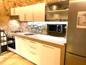 eine Küche mit weißen Schränken und einem Kühlschrank aus Edelstahl in der Unterkunft San Domenico Suite in Martano