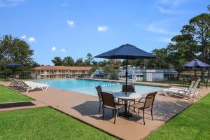 a table and chairs with an umbrella next to a pool at Motel 6-Kilgore, TX in Kilgore