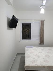 ein weißes Schlafzimmer mit einem Bett und einem Fenster in der Unterkunft Lindo Apartamento em Ubatuba in Ubatuba