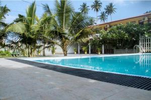 a swimming pool in front of a building with palm trees at Larn's Villa Hotel & Apartment in Wadduwa