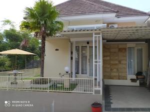 een huis met een veranda en een palmboom bij Villa Allesha Batu in Batu