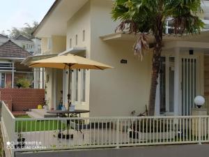 un patio con una mesa y una sombrilla frente a una casa en Villa Allesha Batu, en Batu