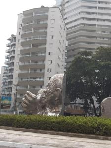 une statue devant un grand bâtiment dans l'établissement Apartamento 2 dorm na Guilhermina com tudo novo, Localização Incrível! Internet 200 MB, à Praia Grande